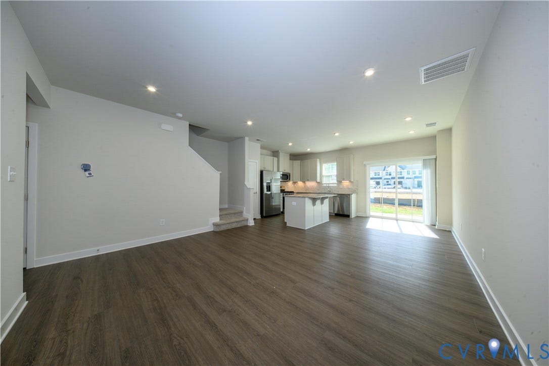 Open-concept living space featuring wood-finish flooring, recessed lighting, and a sliding glass door