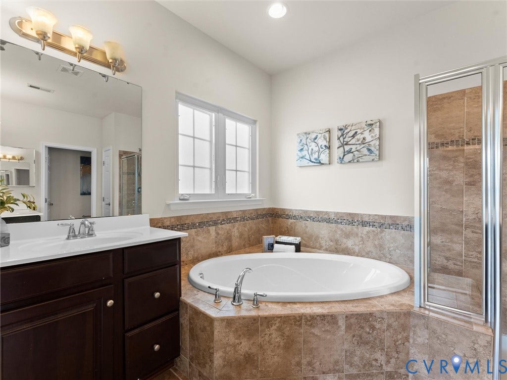 1901 Liesfeld Parkway, West Broad Village, Glen Allen, VA 23060 Jetted soaking tub set in tiled surround, separate glass-enclosed shower, dual-pane window, and a dark wood-finish vanity with a white countertop