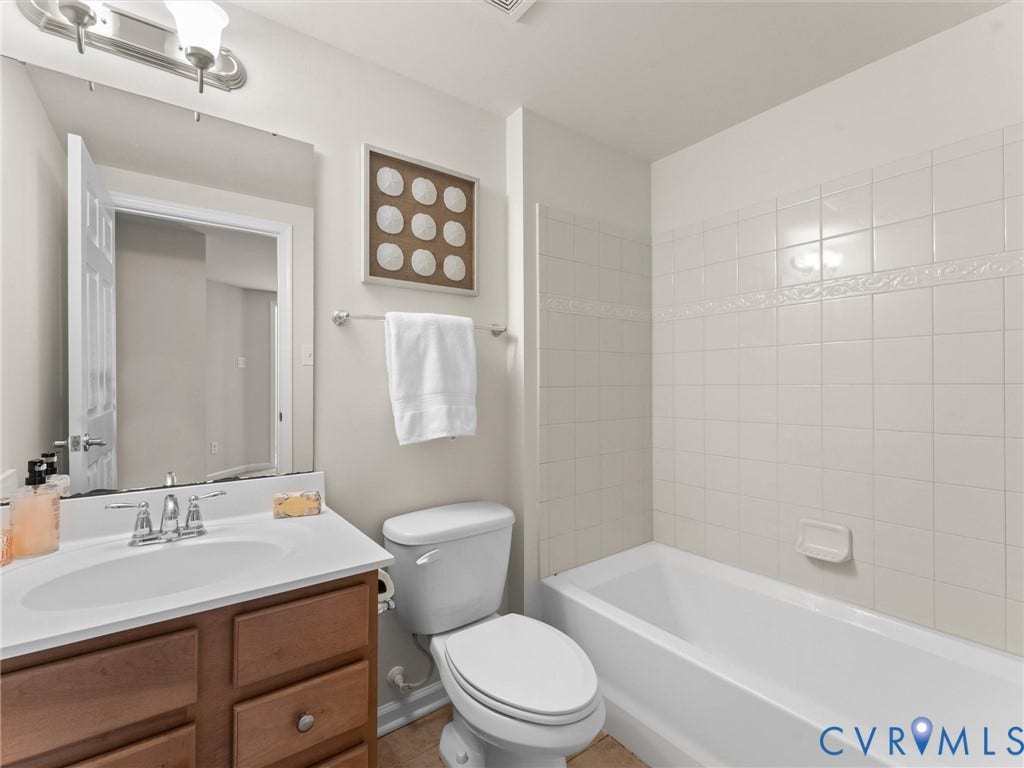 1901 Liesfeld Parkway, West Broad Village, Glen Allen, VA 23060 Bathroom featuring a wood-finish vanity with an integrated sink, a full-width mirror, and a tiled tub/shower combination with decorative accent tile