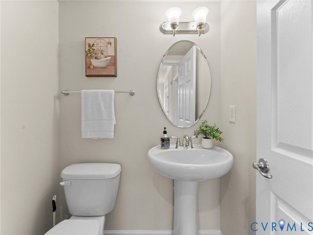 1901 Liesfeld Parkway, West Broad Village, Glen Allen, VA 23060 White pedestal sink, modern chrome faucet, oval mirror, and wall-mounted light fixture