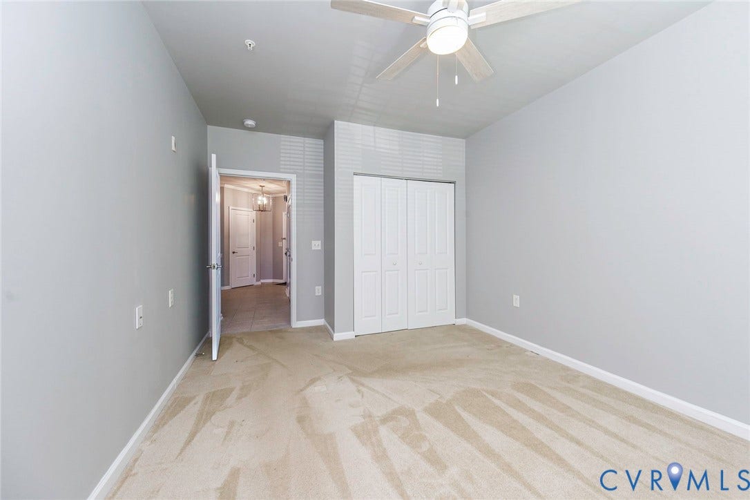 Ceiling fan, wall-to-wall carpeting, bi-fold closet doors, and light gray wall paint