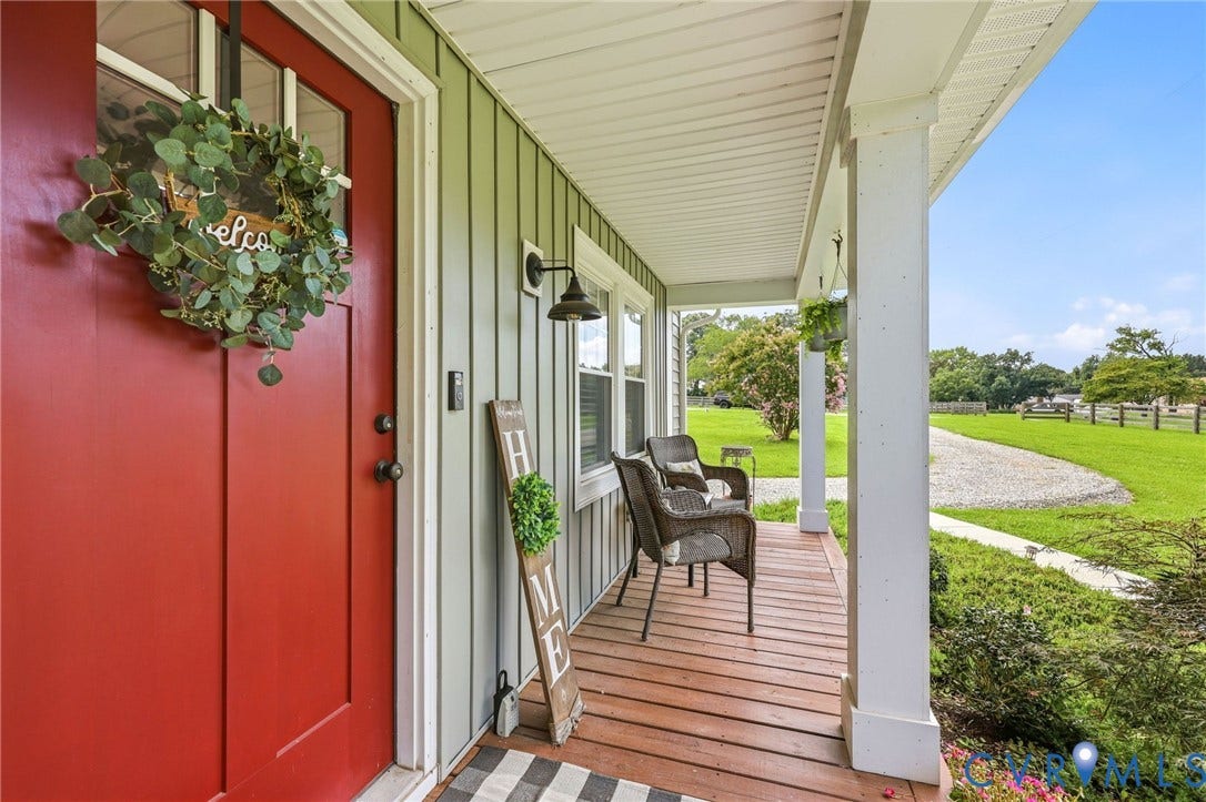 1108 Schroeder Road, Powhatan, VA 23139 Expansive covered porch featuring a rich wood-finish deck, white support columns, and an exterior wall light fixture