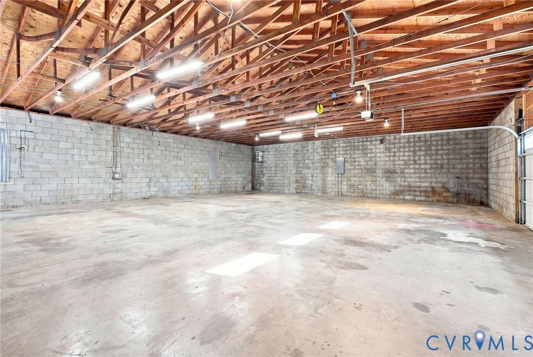 1108 Schroeder Road, Powhatan, VA 23139 Spacious interior with exposed wooden truss ceiling, concrete block walls, concrete flooring, and fluorescent lighting