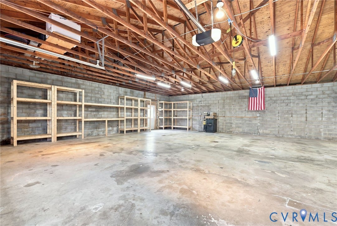1108 Schroeder Road, Powhatan, VA 23139 Exposed wood beam ceiling with fluorescent lighting, concrete block walls, and extensive built-in wooden shelving