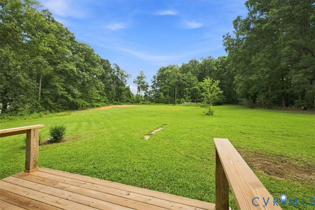 2338 Georges Road, Powhatan, VA 23139 Expansive grassy lawn surrounded by mature trees, featuring a wooden deck with railing