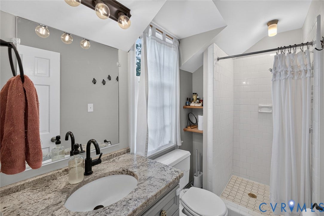 Vanity with speckled countertop and undermount sink, black-finish faucet, subway tile shower surround, and patterned shower floor
