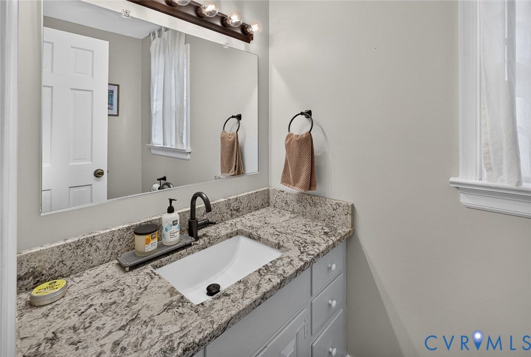 Vanity with an undermount sink, dark bronze faucet, and light-toned countertop