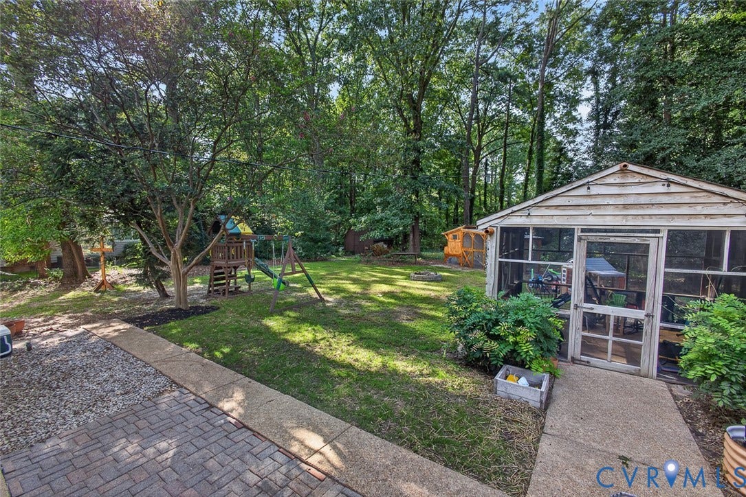Expansive backyard featuring a screened porch, mature trees, and a brick paver patio