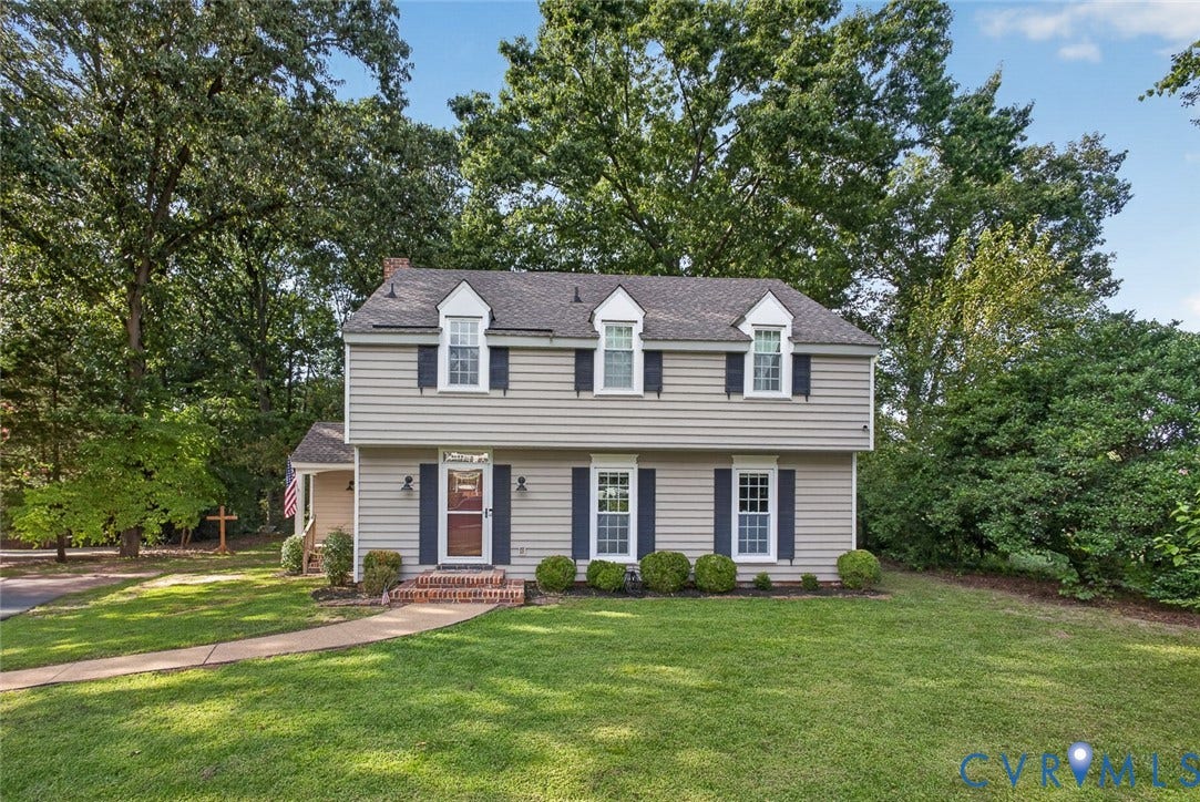 Two-story residence featuring dormer windows, a covered front porch, and a brick entry stoop