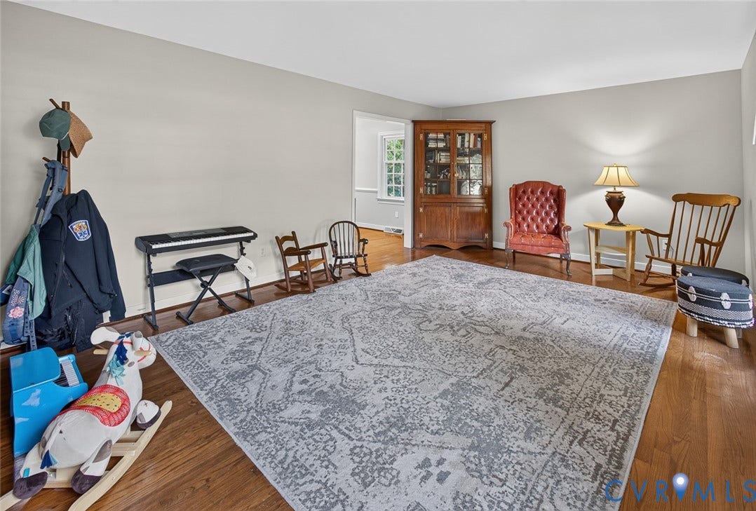 Hardwood flooring throughout, light gray wall paint, and a built-in display cabinet with glass doors