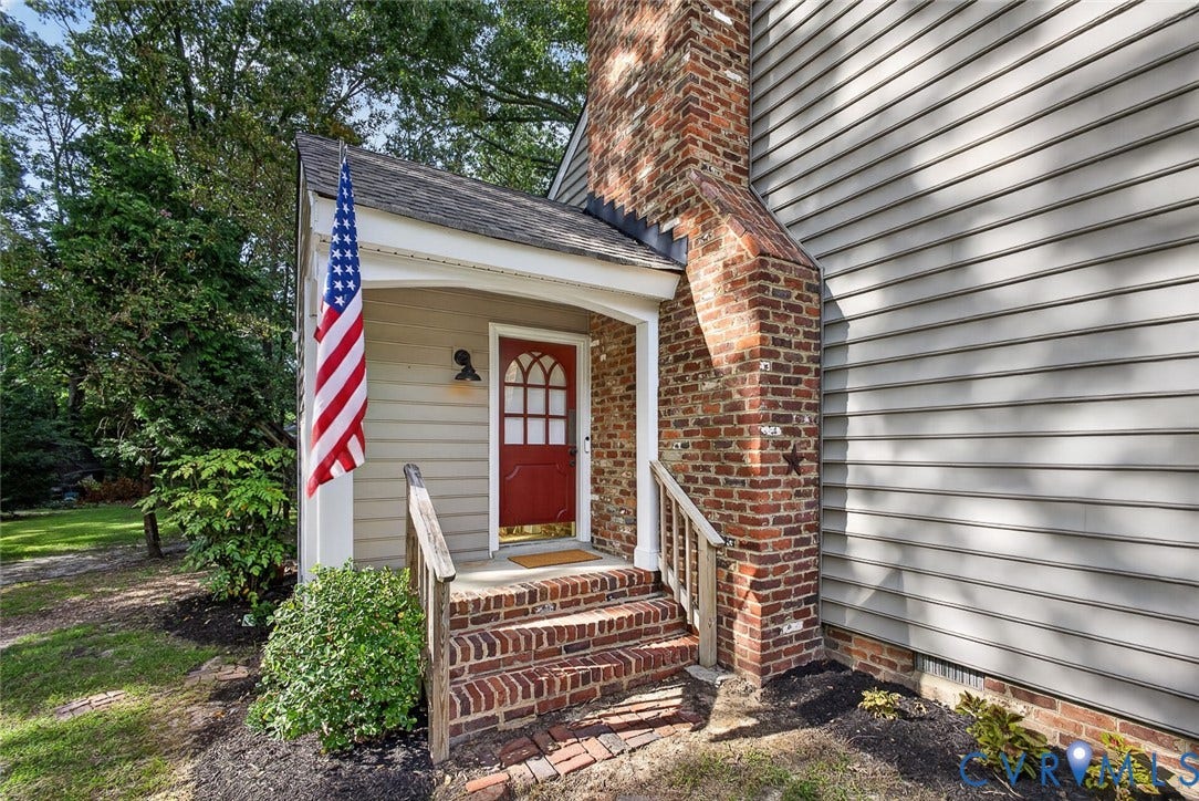 Brick exterior accents and steps complementing a red entry door with decorative glass