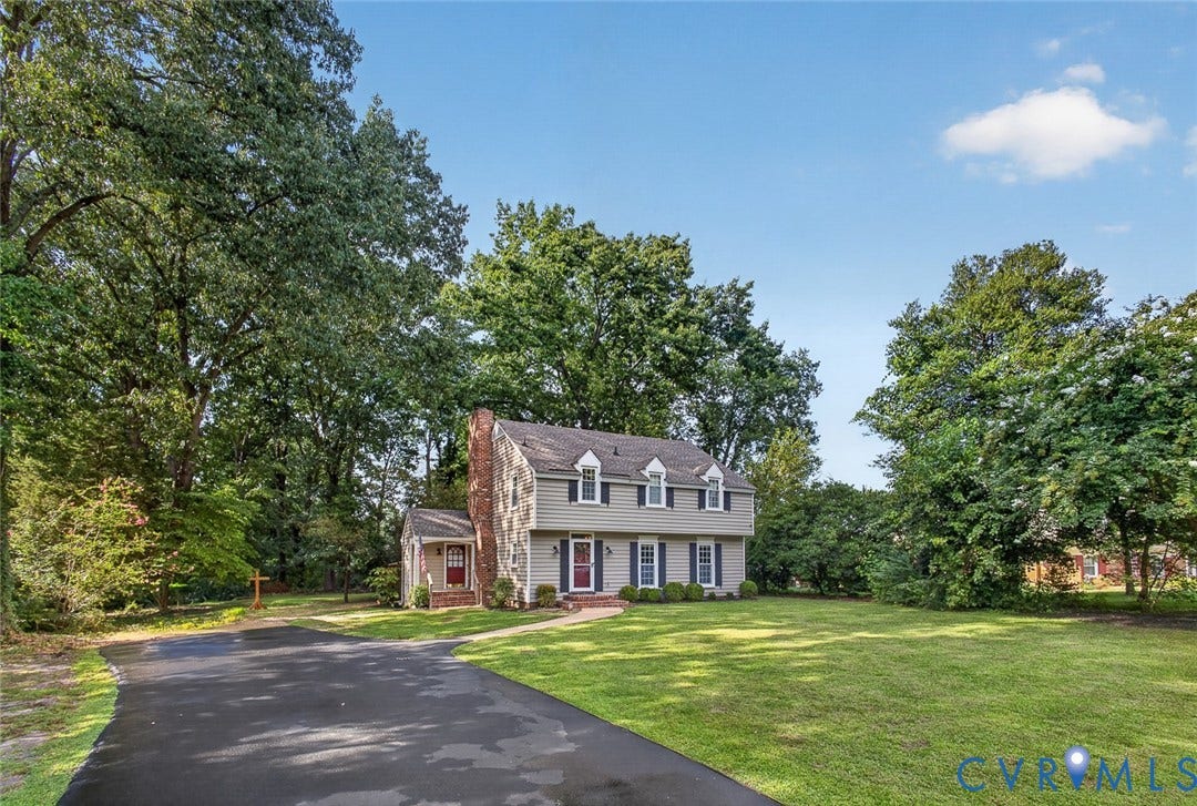 Traditional residence with dormer windows, a prominent brick chimney, and a paved driveway