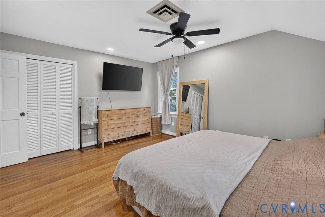 Hardwood flooring, vaulted ceiling, white louvered bifold closet doors, built-in recessed lighting, and a ceiling fan with integrated light