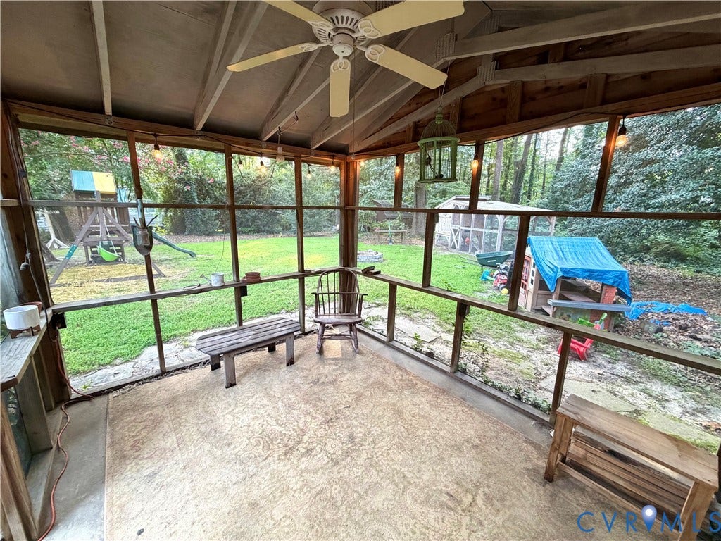 Screened-in porch featuring a ceiling fan, exposed wood beams, string lighting, and an expansive backyard