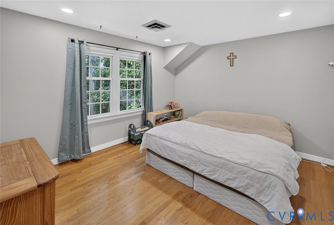 Recessed ceiling lighting, light gray wall finishes, wood-finish flooring, and a multi-pane window