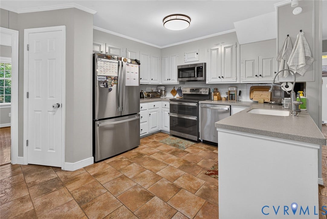 White cabinetry, stainless steel appliances, neutral countertops, recessed lighting, and tile flooring