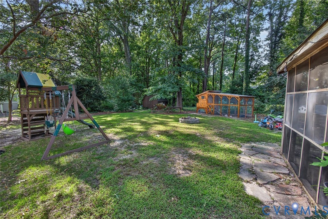 Expansive grassy yard with mature trees, a stone pathway, and a screened-in porch structure