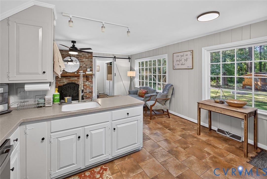 White cabinetry with dark hardware, a single basin sink, and solid surface countertops