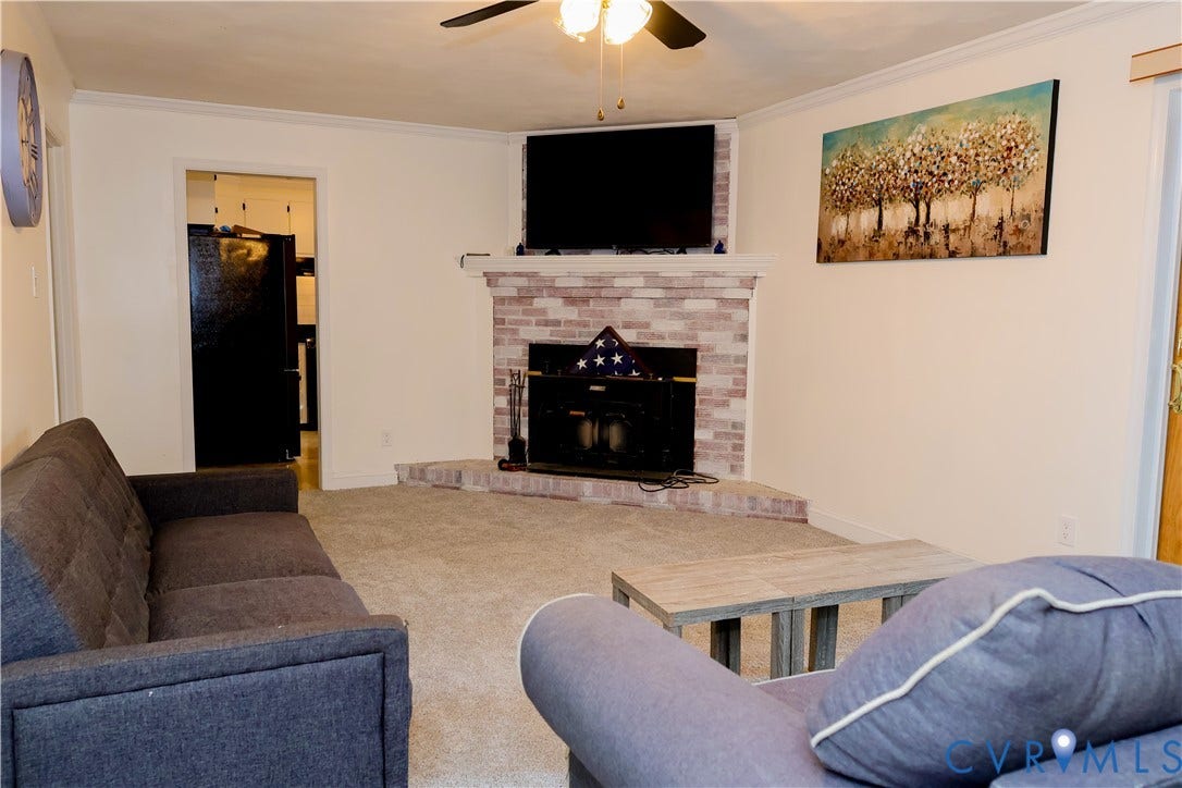 4941 Hopkins Road, Chesterfield, VA 23234 Recessed fireplace with brick surround and hearth, crown molding, ceiling fan with integrated lighting, and carpeted flooring