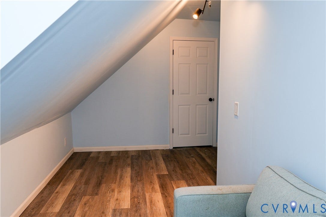 4941 Hopkins Road, Chesterfield, VA 23234 Sloped ceiling with, wood laminate-finish flooring, and a paneled interior door leading to storage area.