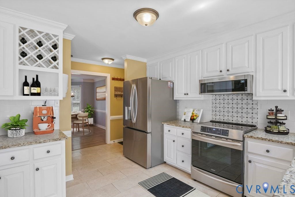 8806 Thornton Heath Drive, Chesterfield, VA 23832 White cabinetry with dark hardware, stainless steel appliances, light-toned tile flooring, light-toned countertops, and a decorative tile backsplash