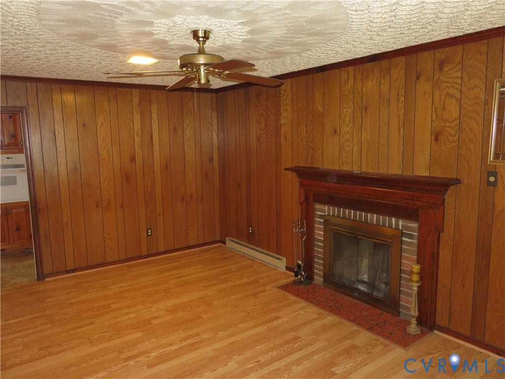 3107 Neale Street, Eastern Henrico, Richmond, VA 23223 Wood-finish flooring, wood paneling, decorative ceiling fan, brick fireplace with wood mantel, and patterned hearth