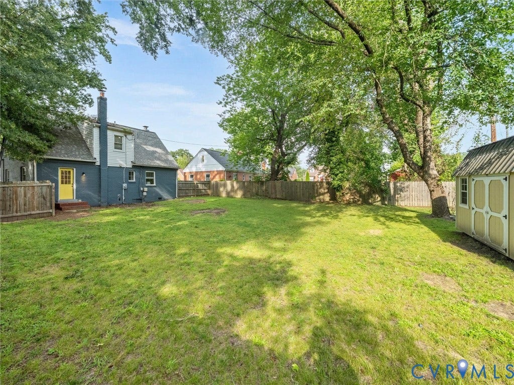 709 Ratcliffe Avenue, Richmond, VA 23222 Expansive grassy backyard with mature trees, a wood privacy fence, and a storage shed