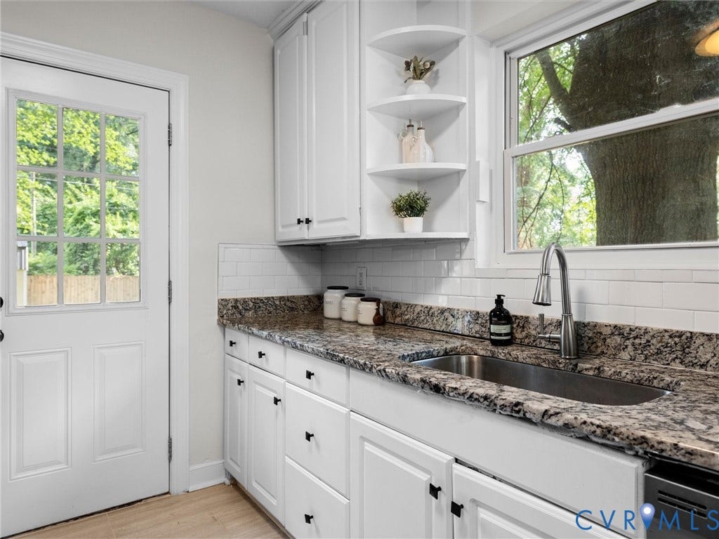 709 Ratcliffe Avenue, Richmond, VA 23222 White shaker cabinetry with black hardware, stone-finish countertops, stainless steel undermount sink, white subway tile backsplash, and wood-finish flooring