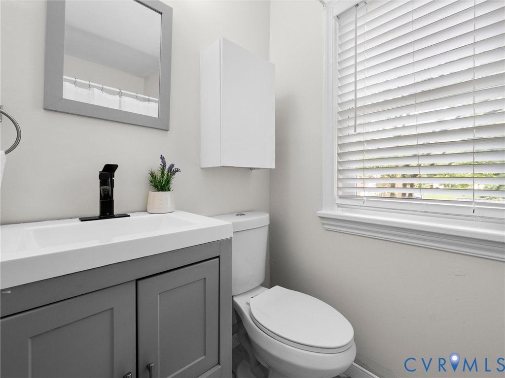 709 Ratcliffe Avenue, Richmond, VA 23222 Vanity with integrated white basin, matte black faucet, gray shaker-style cabinetry, and a framed mirror