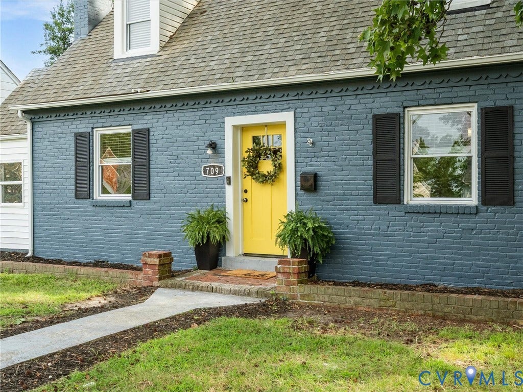 709 Ratcliffe Avenue, Richmond, VA 23222 Brick exterior with a vibrant yellow entry door, contrasting dark shutters, and a dormer window