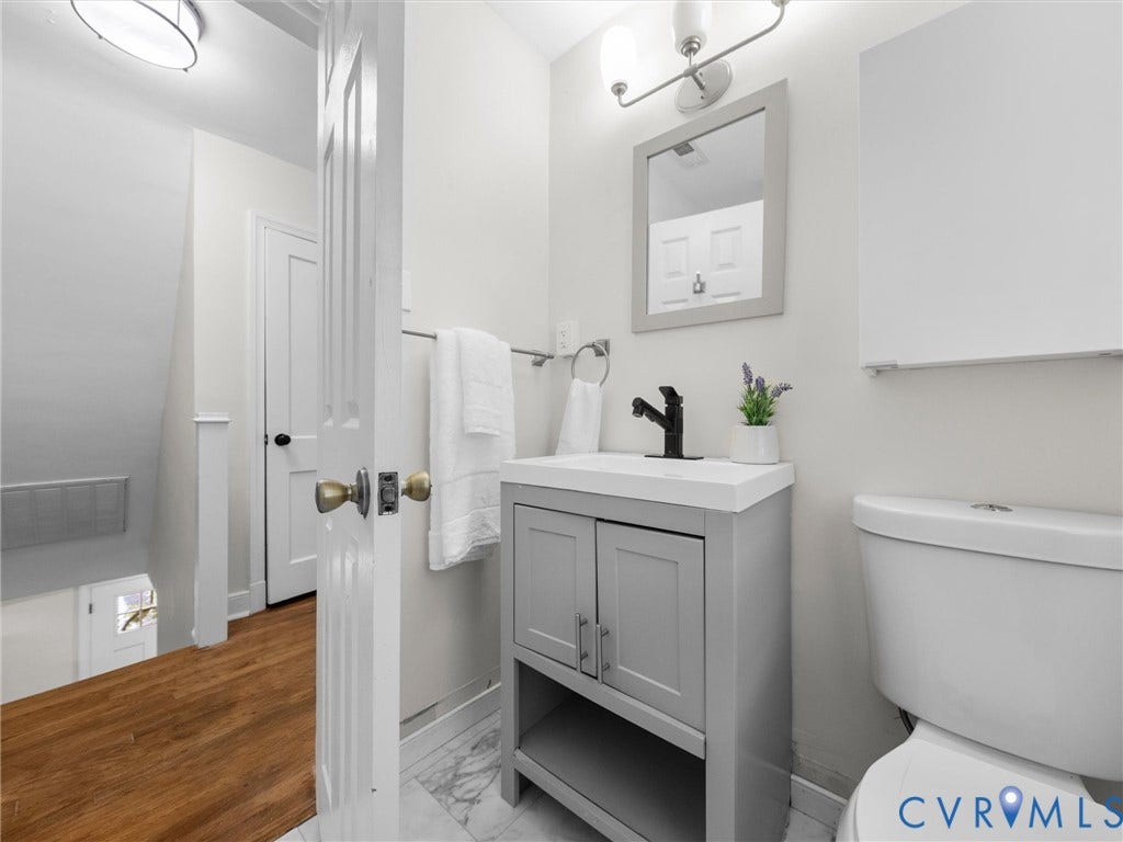 709 Ratcliffe Avenue, Richmond, VA 23222 Bathroom featuring a gray vanity with integrated sink, a rectangular mirror, a wall-mounted light fixture, and a white toilet