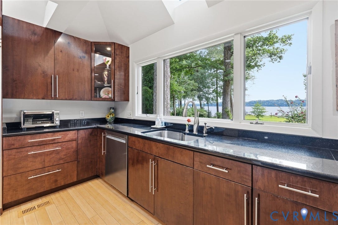 3416 Walkers Ferry Road, Walkers Ferry, Midlothian, VA 23112 Wood-finish cabinetry with brushed nickel hardware, black stone countertops, stainless steel undermount sink with a gooseneck faucet, wood-finish flooring, and a large window overlooking a body of water