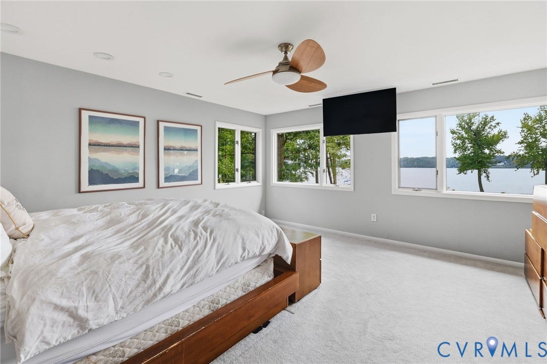 3416 Walkers Ferry Road, Walkers Ferry, Midlothian, VA 23112 Spacious primary bedroom with expansive windows overlooking waterfront scenery, light-filled interiors with recessed ceiling lighting, wood-finish ceiling fan with brushed metal accents, and plush carpeting throughout