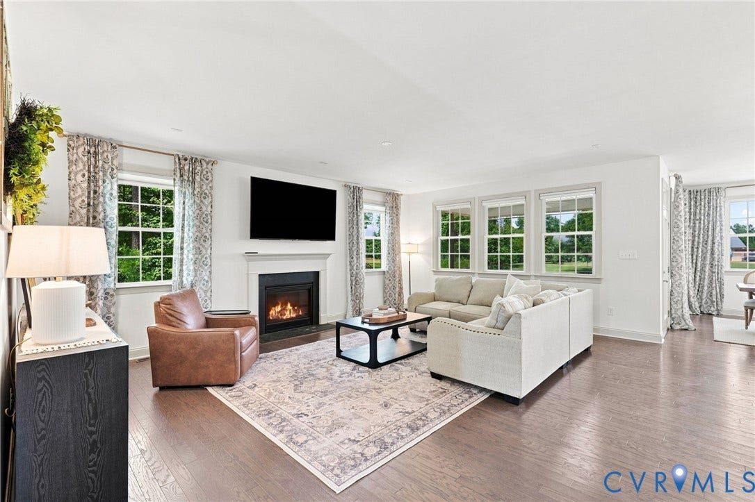 6907 Carden Park Drive, Carden Park, Moseley, VA 23120 Spacious living area featuring hardwood flooring, a traditional fireplace with a white mantel, and multiple windows overlooking the 9th Tee