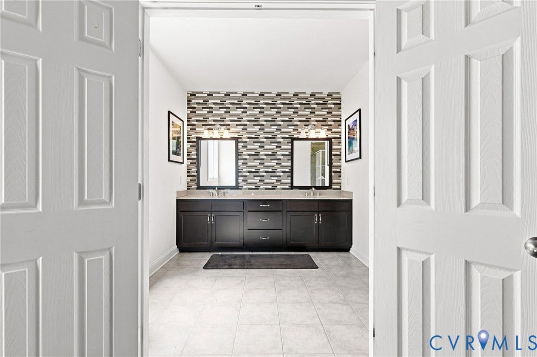 6907 Carden Park Drive, Carden Park, Moseley, VA 23120 Dual dark wood-finish vanities with undermount sinks, individual mirrors, and a mosaic tile accent wall