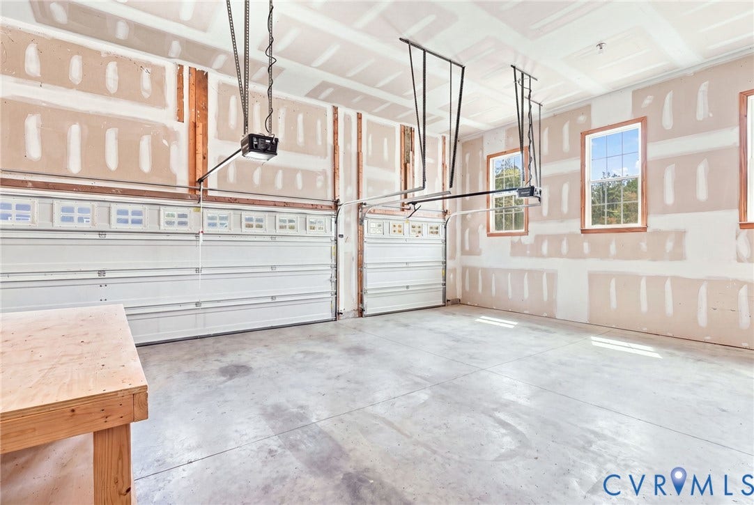 6907 Carden Park Drive, Carden Park, Moseley, VA 23120 Spacious 3 car garage featuring two overhead doors, two garage door openers, multiple windows, and a concrete floor