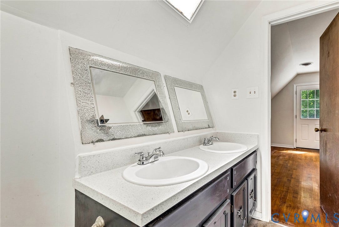 10478 Gould Hill Road, Studley, Hanover, VA 23069 Dual vanity with integrated sinks, white countertop, dark wood-finish cabinetry, and a skylight. Fresh paint. Door leads into bedroom 2