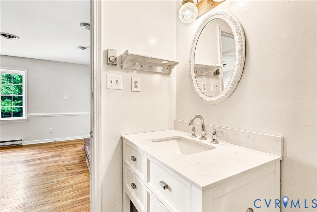 10478 Gould Hill Road, Studley, Hanover, VA 23069 White vanity with a single basin, brushed nickel faucet, and an oval framed mirror