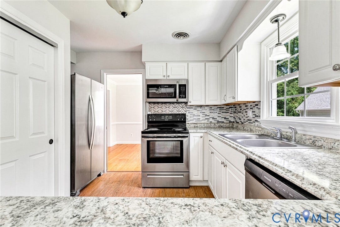 10478 Gould Hill Road, Studley, Hanover, VA 23069 Updated kitchen featuring white cabinetry, granite countertops, stainless steel appliances including double wall ovens and microwave, mosaic tile backsplash, and wood-finish flooring throughout the open layout