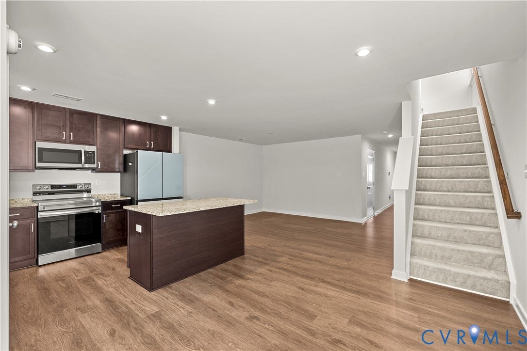 3372 Dewsberry Lane, Henrico, VA 23231 Open-concept living area featuring wood-finish flooring, recessed lighting, and a kitchen with stainless steel appliances, dark wood cabinetry, and a center island with a light-toned countertop