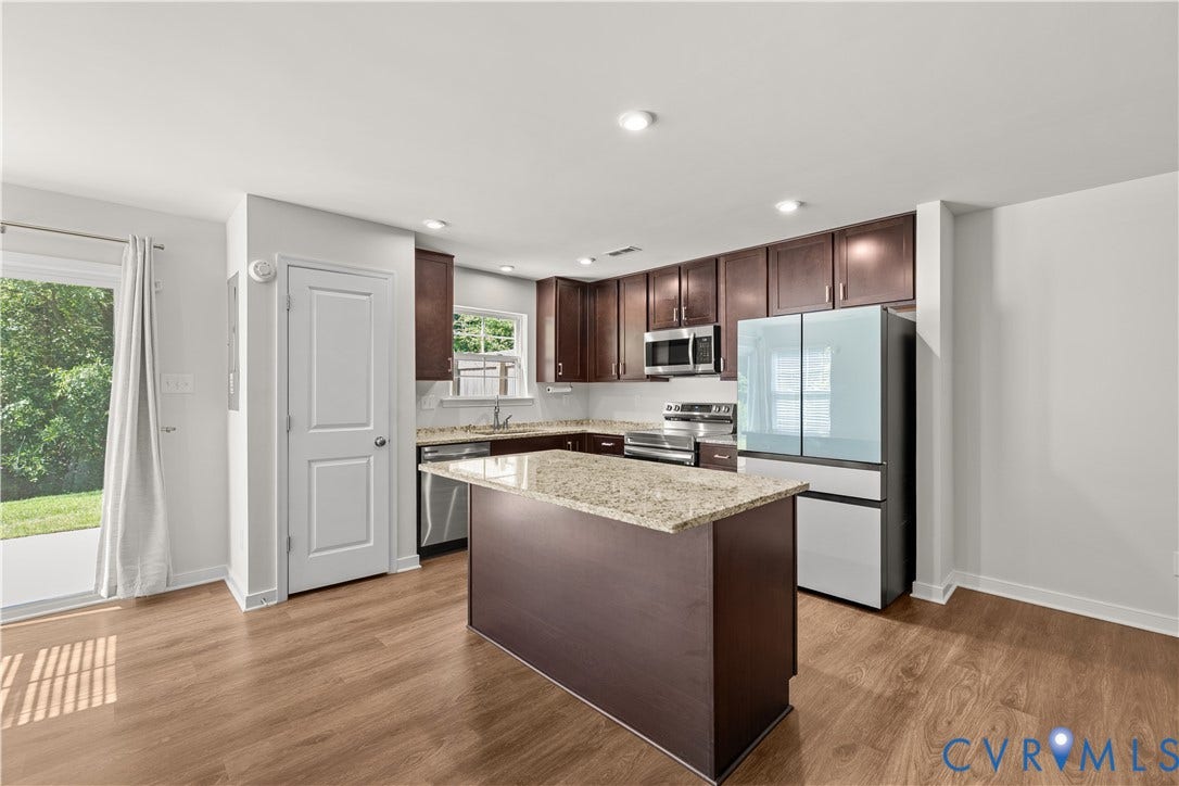 3372 Dewsberry Lane, Henrico, VA 23231 Kitchen featuring wood-finish flooring, dark wood cabinetry, stainless steel appliances, a center island with a light-toned countertop, and a sliding glass door to exterior