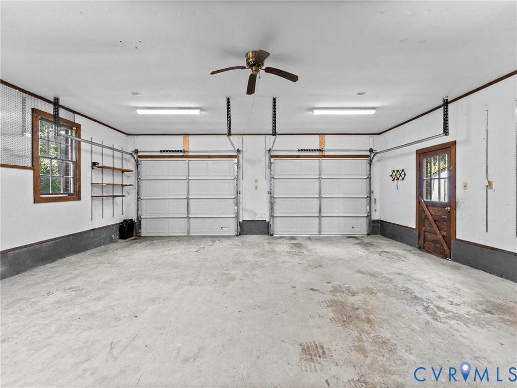 3610 Castlebury Drive, Chester, VA 23831 Two-car garage featuring concrete flooring, twin garage doors, a paneled wood-finish entry door, and a ceiling fan