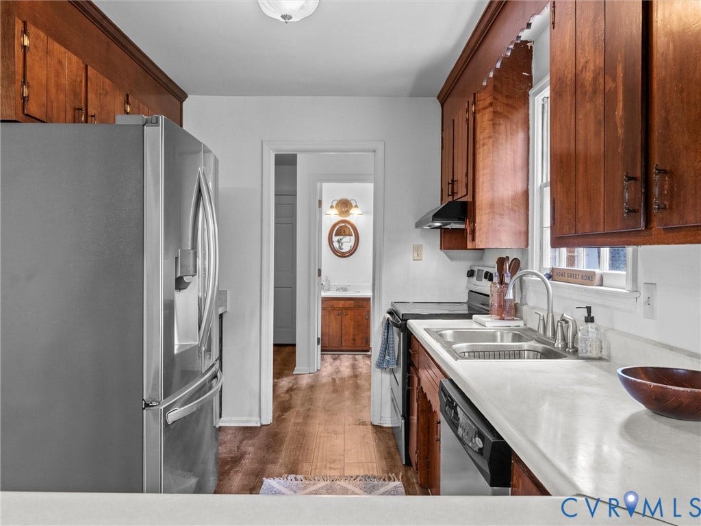 3610 Castlebury Drive, Chester, VA 23831 Stainless steel refrigerator, wood-finish cabinetry, dual basin sink with a gooseneck faucet, light-toned countertops, and wood-finish flooring