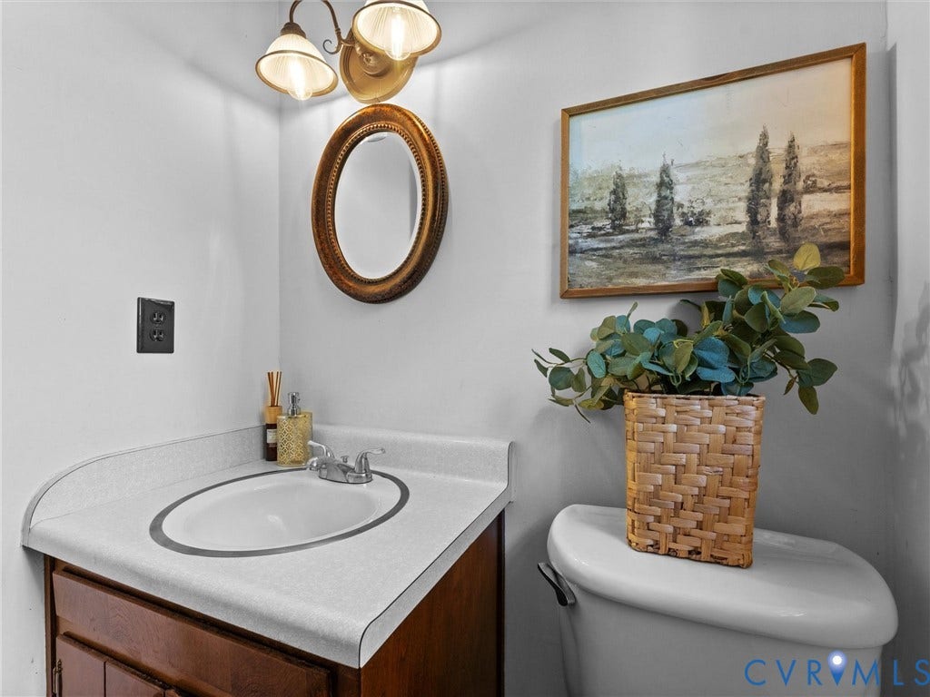 3610 Castlebury Drive, Chester, VA 23831 Vanity with a laminate countertop and an integrated oval sink, paired with a two-light wall sconce