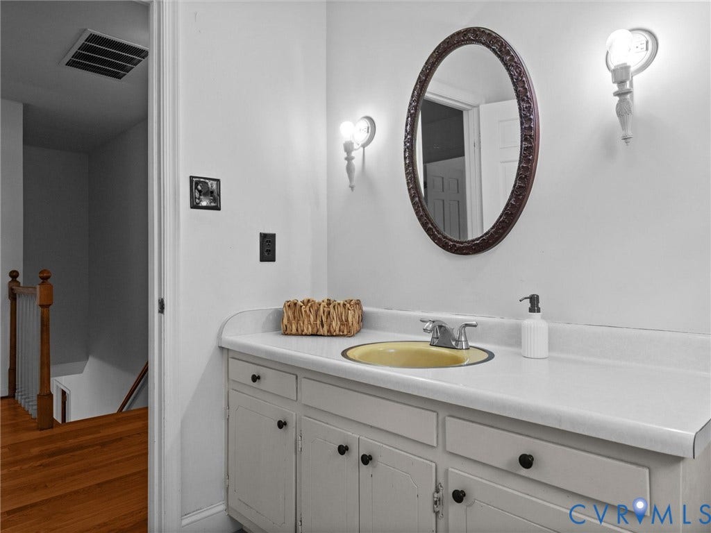 3610 Castlebury Drive, Chester, VA 23831 Vanity with white countertop, integrated yellow basin, and dual wall-mounted sconces