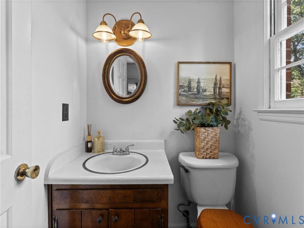 3610 Castlebury Drive, Chester, VA 23831 White countertop vanity with wood-finish cabinetry, a chrome faucet, and an oval mirror