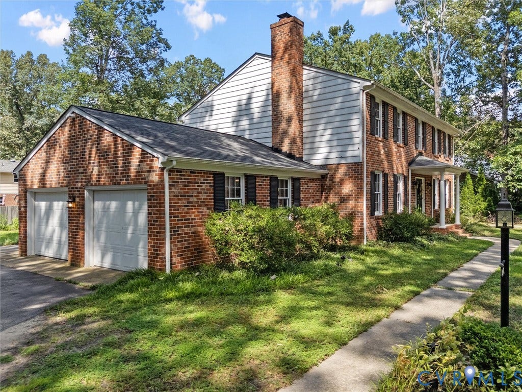 3610 Castlebury Drive, Chester, VA 23831 Brick exterior with a prominent chimney, a two-car garage, and a covered front porch with white columns