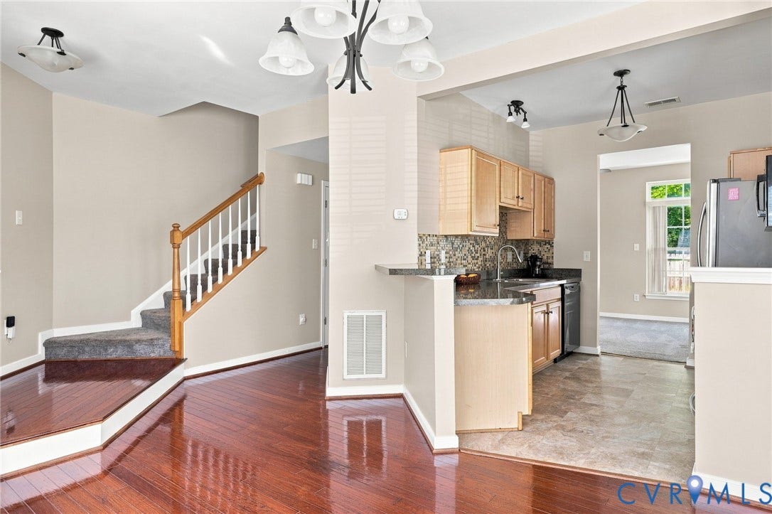 3818 Dominion Townes Circle, Dominion Townes, Richmond, VA 23223 Hardwood-finish flooring, staircase with carpeted treads and wood railing, kitchen with wood-finish cabinetry, granite-style countertops, and a tiled backsplash