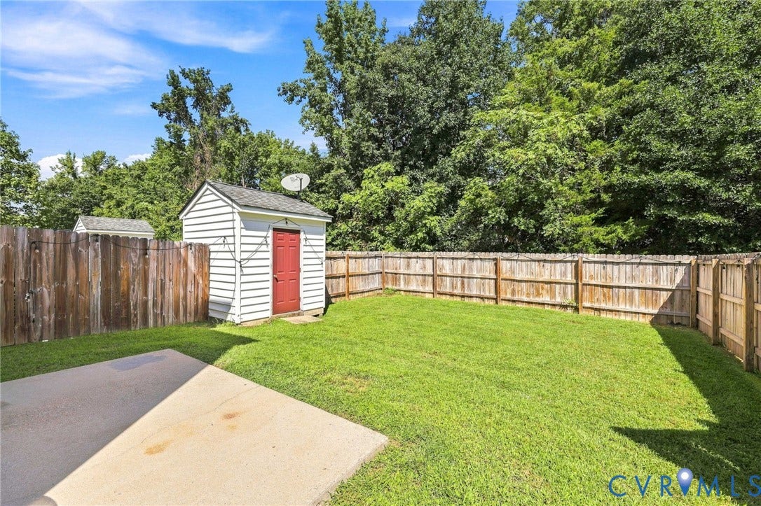 3818 Dominion Townes Circle, Dominion Townes, Richmond, VA 23223 Expansive backyard with a manicured lawn, wood privacy fencing, and a white storage shed with a red door