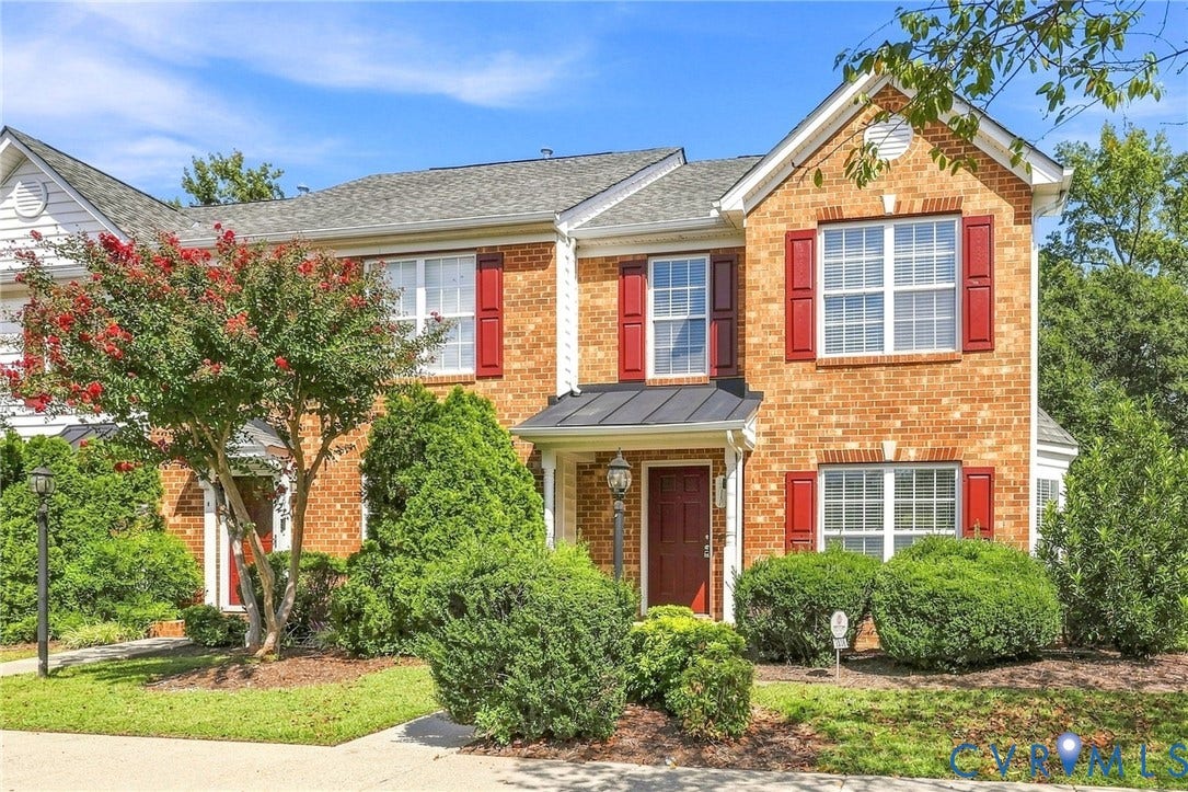 3818 Dominion Townes Circle, Dominion Townes, Richmond, VA 23223 Brick exterior with red shutters, a prominent front door with an overhead awning, and established landscaping